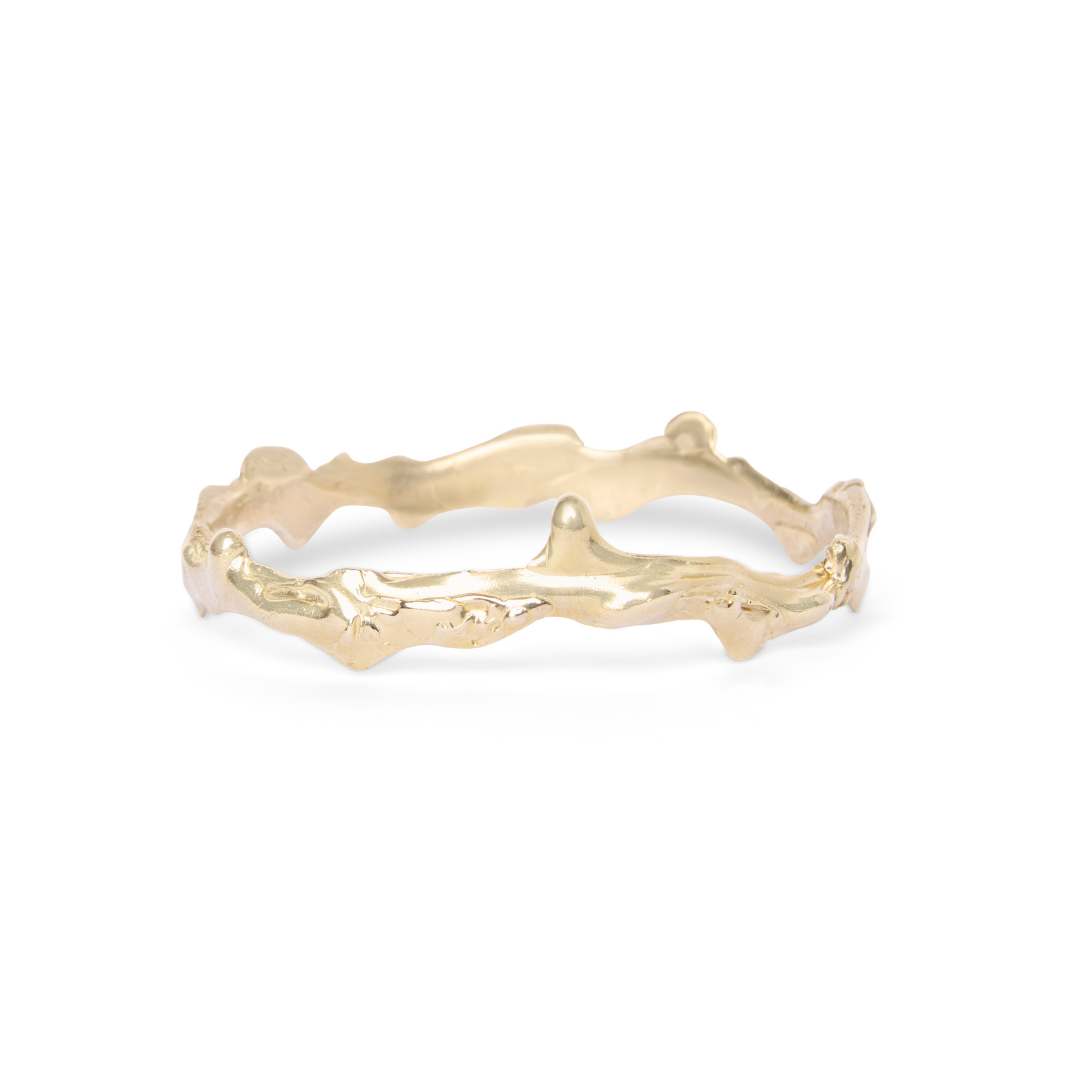The Liana Bangle by Madeleine Sculptural Jewellery features an irregular, organic design with a textured surface inspired by natural branches, showcasing sculptural artistry. Photographed on a white background.