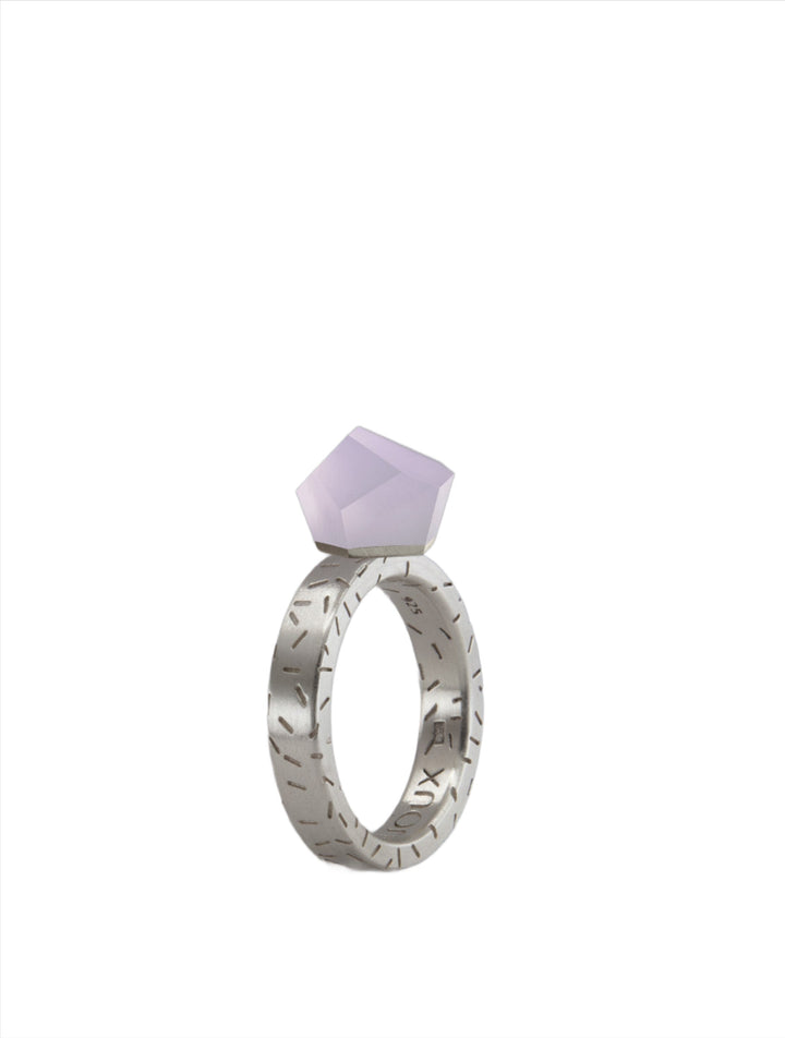 A silver ring topped with a geometric, angular lavender gemstone is showcased. The 24ct gold-plated band is engraved with line patterns, giving it a textured appearance. The white background ensures the Fruit Bijoux Ring Top VU Crystals Lilac Purple by Fruit Bijoux remains the focal point of the image.