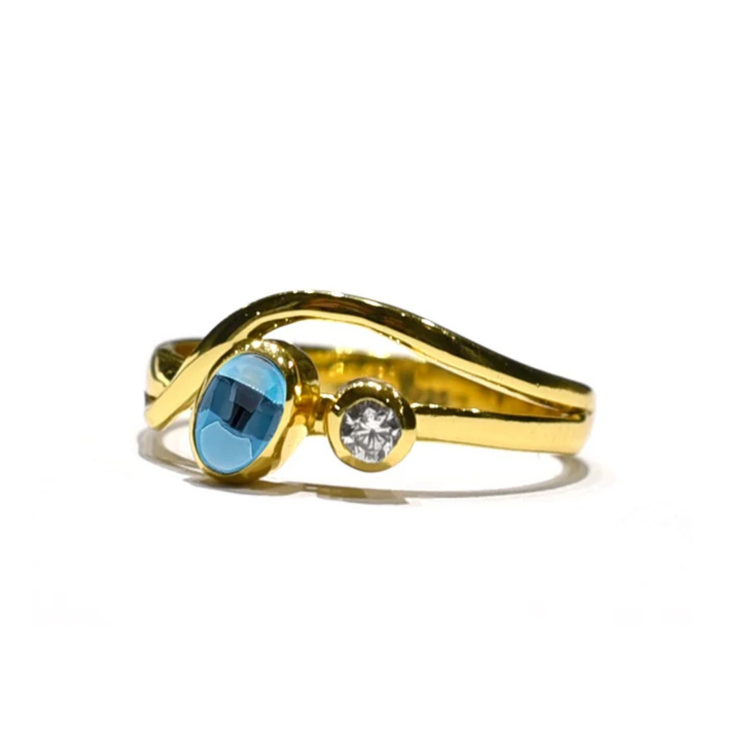 The Watermelon Tropical Iolite & Cubic Zirconia Gold Ring features a twisting gold plated sterling silver band with a round iolite and smaller cubic zirconia side by side—ideal for fans of handmade jewellery.