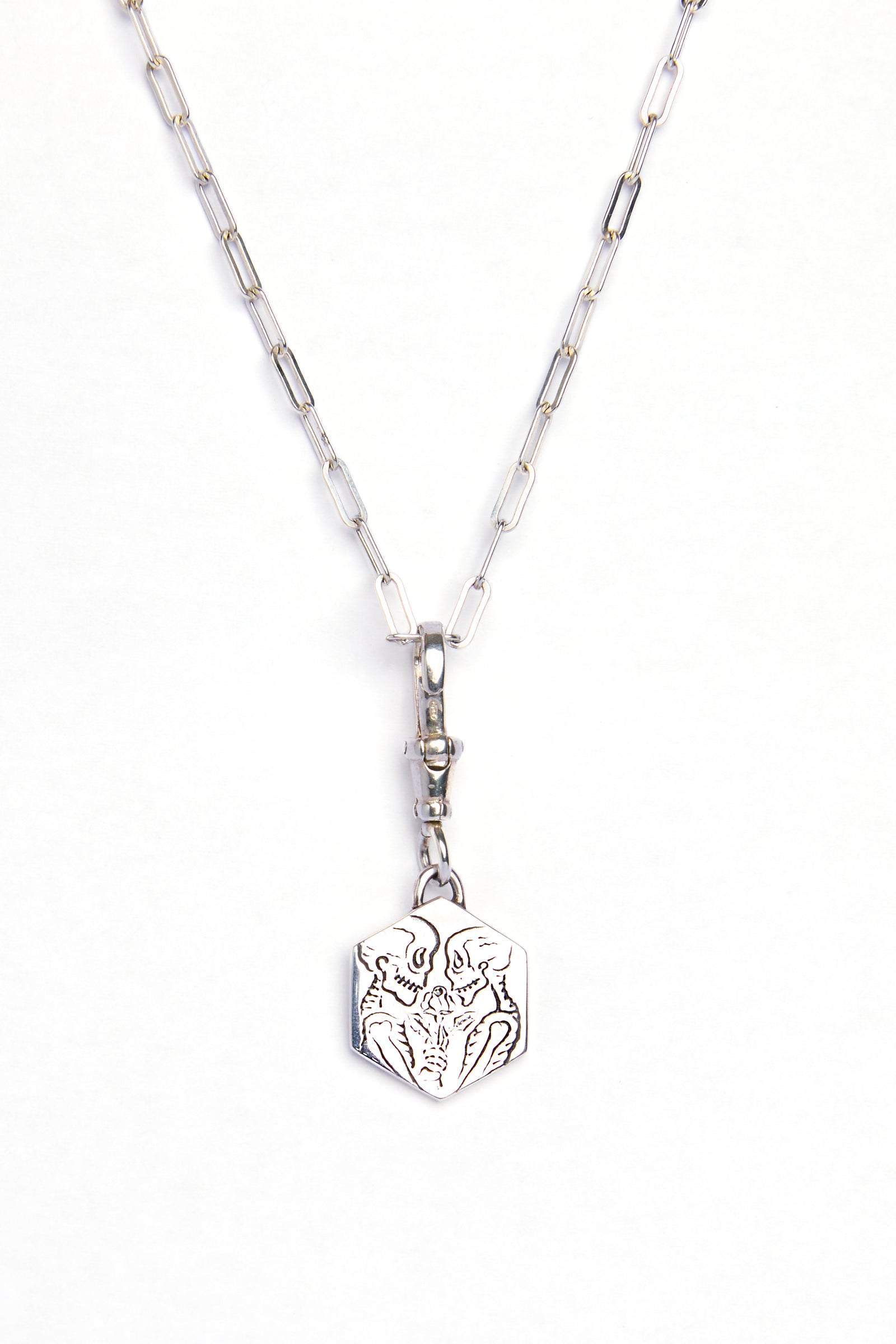 The Lovers Silver Pendant by Cosmic Boulevard features sterling silver elongated chain links and a hexagonal charm engraved with a stylized wolf face, shown on a white background.