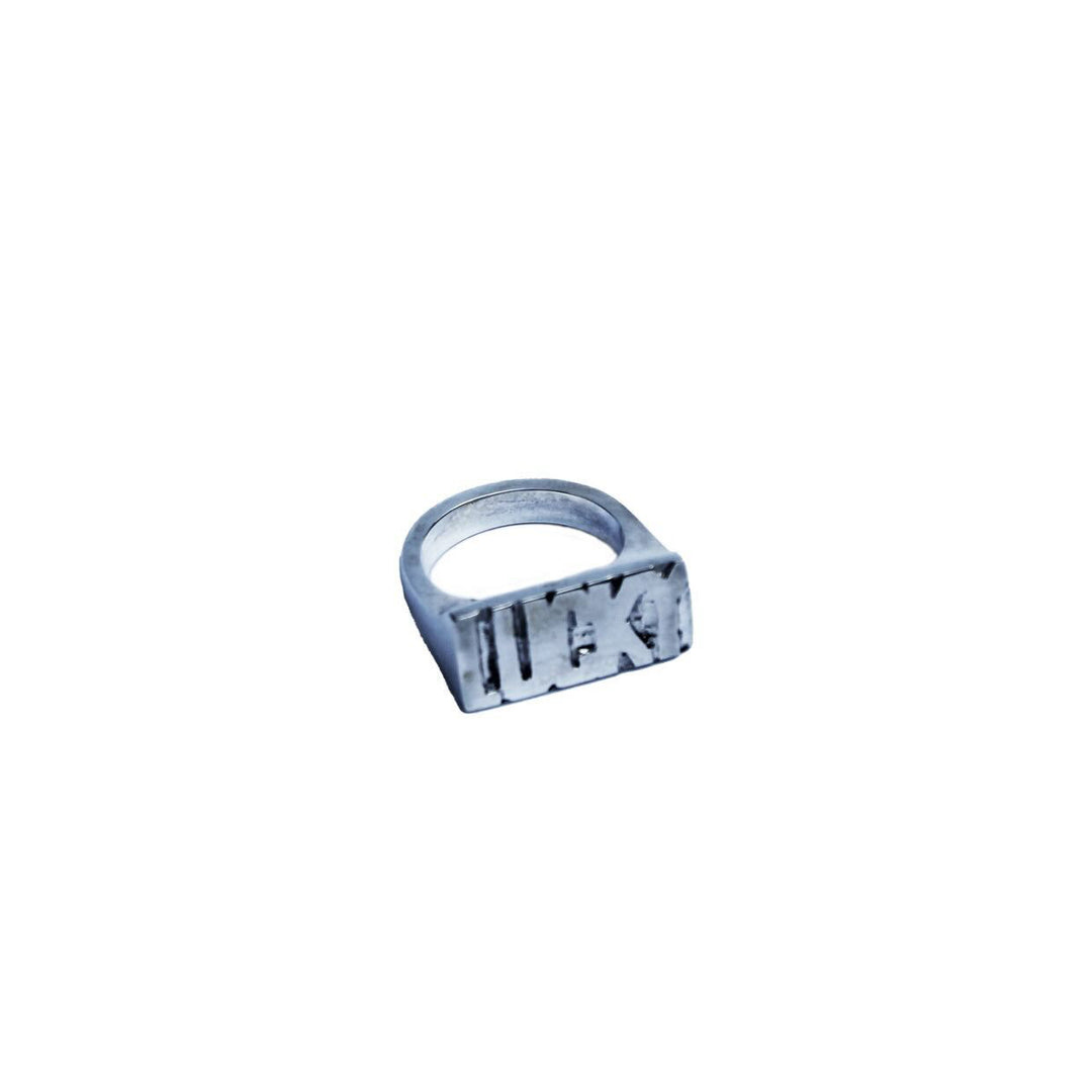 The Kate Murphy Lucky Silver Ring features a rectangular top engraved “LUCKY” in bold. Photographed on a plain white background, this modern sterling silver piece is your contemporary talisman for good fortune.