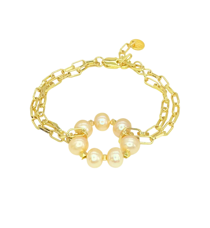 The Lunaire Pearl Bracelet by Aria V features two layered gold chains and a central ring adorned with six pink freshwater pearls, shown on a plain white background.