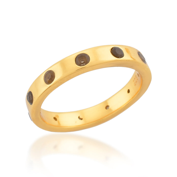 The Mela Ring by Shyla, crafted from 22 carat gold, features evenly spaced round black stones encircling the band. With its smooth, polished finish and simple, elegant design, this ring epitomizes timeless sophistication.