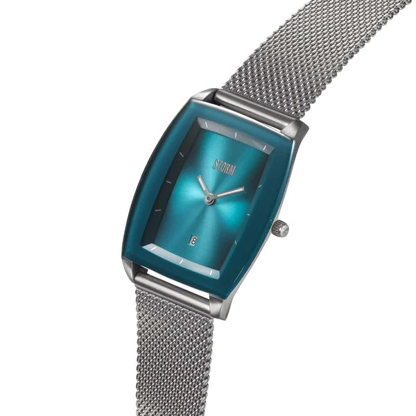 A stylish wristwatch, the Storm Mini Zaire Teal by Storm Watches features a rectangular blue metallic dial and minimalistic design. It boasts a silver mesh band made of sustainable materials and a small date display near the bottom. The watch hands and markers are sleek and unobtrusive, with the brand logo at the top center of the dial.