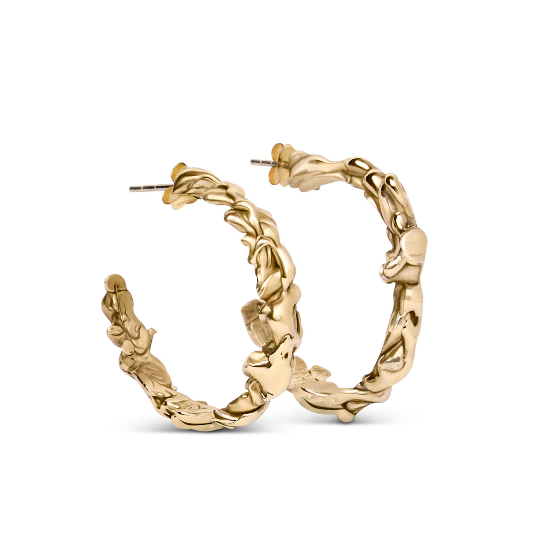 The Molten Hoops Small by Madeleine Sculptural Jewellery feature a textured, organic, and irregular gold surface. These sustainable earrings are showcased against a white background.