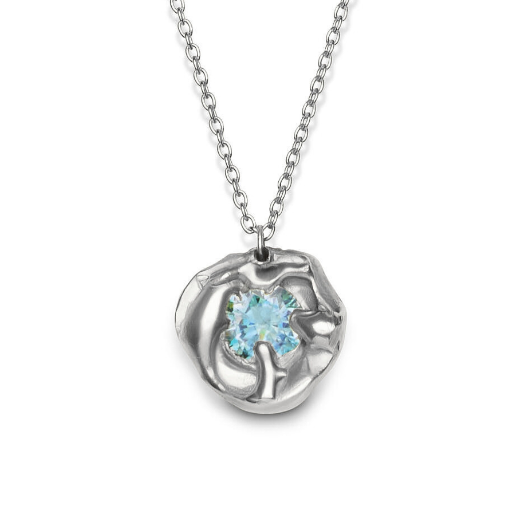 The Molten Necklace with Moissanite by Madeleine Sculptural Jewellery features a silver pendant with a round, textured setting and light blue moissanite, highlighting sustainable craftsmanship against a plain white background.
