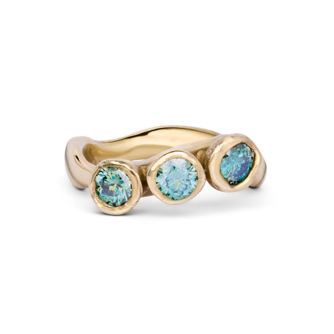 The Moonwater Ring by Madeleine Sculptural Jewellery features a hand-carved wavy gold band with three round blue-green gemstones in individual bezels—a striking, sustainable piece for lovers of unique jewellery.