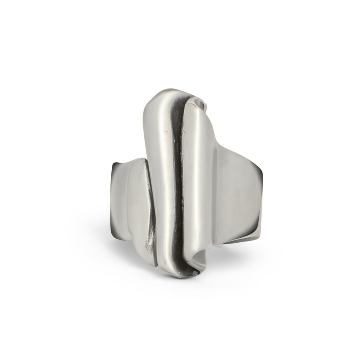 The Tonnach Ring Big by Madeleine Sculptural Jewellery is a handmade silver adjustable ring with a wide band and an abstract, folded sculptural design, showcased against a white background.