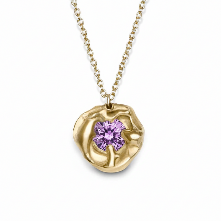The Molten Necklace with Moissanite by Madeleine Sculptural Jewellery features a round, textured gold setting with a sparkling moissanite center on a simple gold chain—a striking piece shown against a white background.