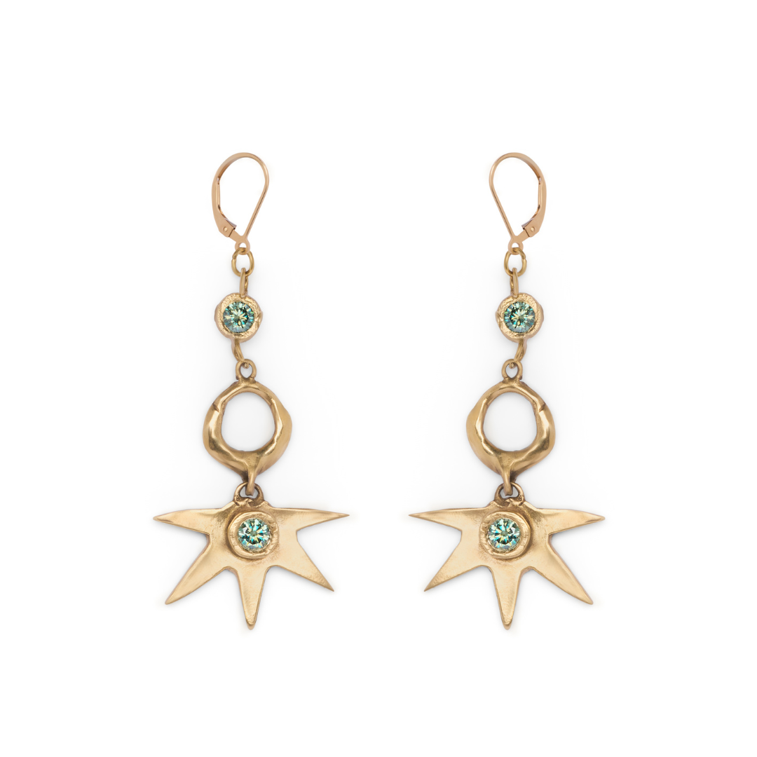 Discover the Réalta Earrings with 2 moissanite by Madeleine Sculptural Jewellery—gold dangle earrings featuring a radiant sunburst motif accented with blue-green gemstones. Each earring showcases a three-part arrangement of circular and star-shaped charms, delicately linked by gold rings. Subtle moon and star accents infuse these earrings with celestial elegance.