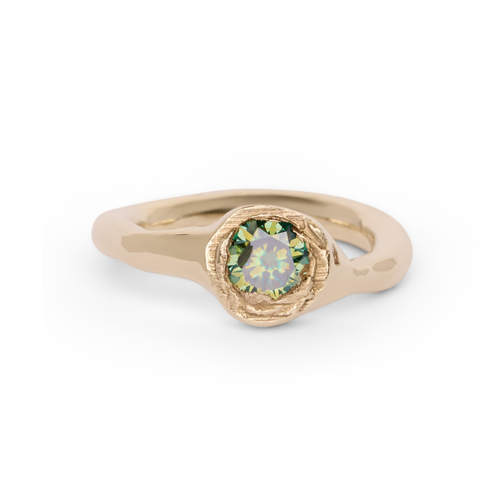 Discover the Dawn Ring by Madeleine Sculptural Jewellery: a gold ring adorned with a round green gemstone in a textured bezel setting. The polished, subtly wavy band lends an organic and modern feel, embodying serenity and simplicity against a clean white backdrop.