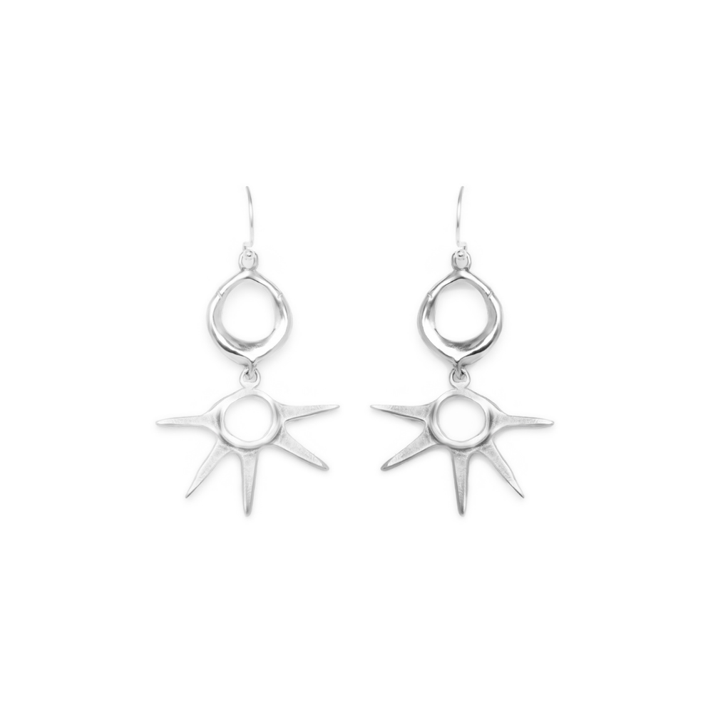A pair of Madeleine Sculptural Jewellery’s Realta Earrings, featuring silver dangle design with circular tops and sunburst-shaped pendants, displayed on a white background.