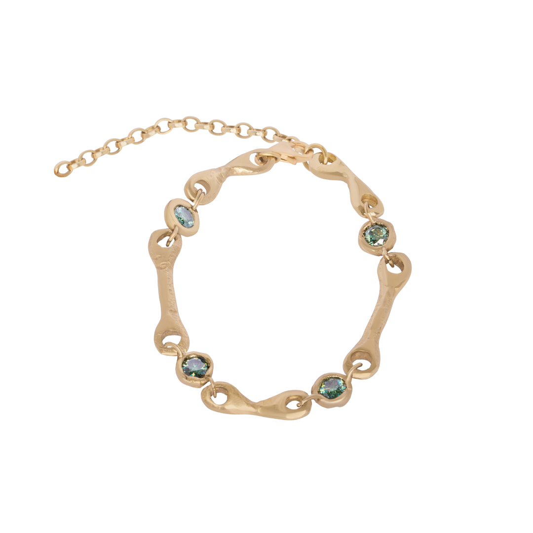 The Relic Bracelet by Madeleine Sculptural Jewellery features an adjustable gold chain with a wavy, organic design and multiple round blue-green gemstones set along the band—a stunning piece of gemstone jewelry that embodies timeless elegance.