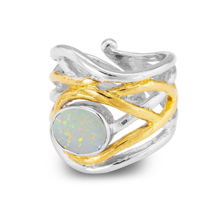 The Adjustable Mayhem Ring by Gallardo & Blaine Designs features a medieval-inspired design with intertwined silver and gold accents, highlighting a large oval opal stone that shimmers with multicolored iridescence.