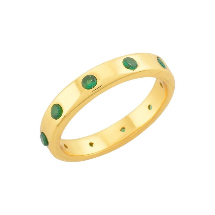 The Shyla Mela Ring boasts a sterling silver band adorned with small, round green gemstones evenly spaced along its length. With a smooth, polished finish and slightly inset stones, this piece exudes timeless elegance.