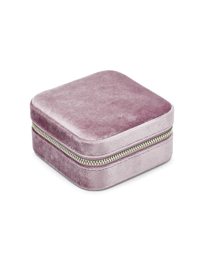 A compact, square, light purple jewelry box with rounded edges and a gold zipper. The velvet-covered texture enhances its plush feel. Closed, the zipper runs around the middle of the box against a plain white background. Introducing the Luxurious Metallic Lilac Velvet Travel Jewellery Box by SoCases.