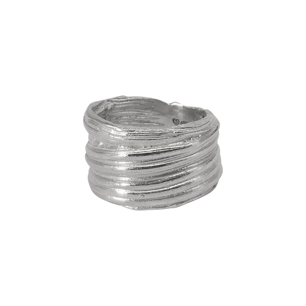 An Abbie Dixon Mitsuro Silver Ring with a wide band and a textured, layered design created using the lost wax method. The ring appears to have multiple thin, wavy layers stacked on top of each other, giving it a unique and artistic look. The silver has a polished finish, embodying the essence of Mitsuro Hikime craftsmanship.