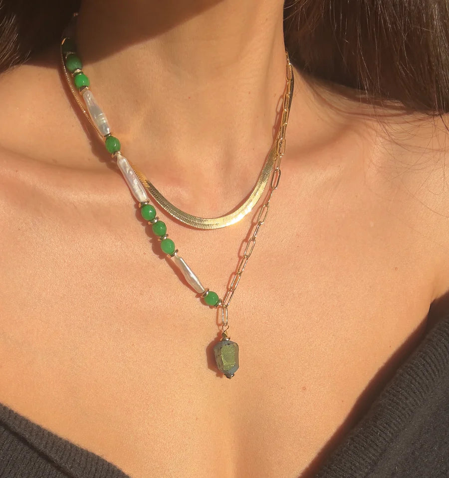 Layered gold necklaces by Aria V: the Muse Green Necklace with baroque pearls and green beads, paired with a gold plated chain featuring a green hexagonal pendant—ideal for fans of handmade Irish jewelry.