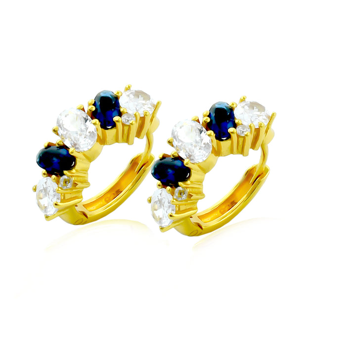 Shyla Nila Huggies are gold earrings featuring alternating oval blue and clear gemstones in prong settings, shown on a white background.