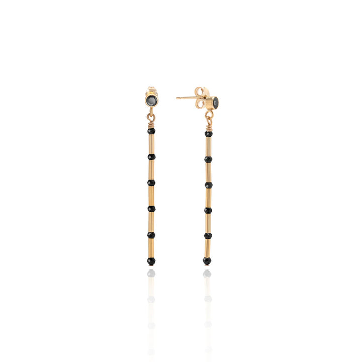 Gold and black beaded earrings on a white background