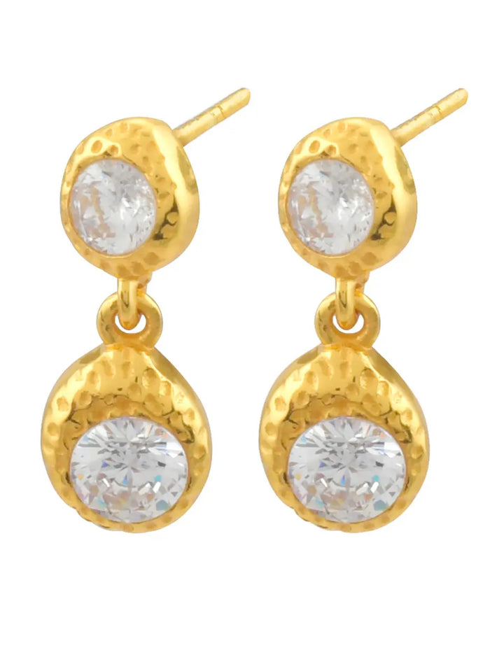 Shyla’s Odessa Earrings feature a hammered gold plated finish and two round clear crystals—one small at the top and a larger gem suspended below.