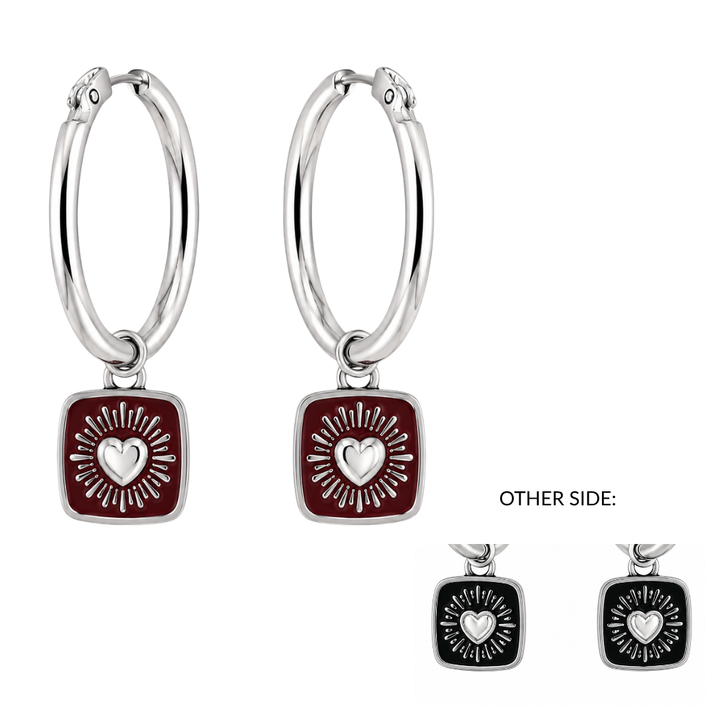 The Collective Dublin’s Double Sided Keith Haring Claddagh Hoop Earrings feature silver hoops with square charms showcasing a heart and sunburst design reminiscent of Keith Haring. The main side is red, while the reverse side is black, as shown in the inset image.