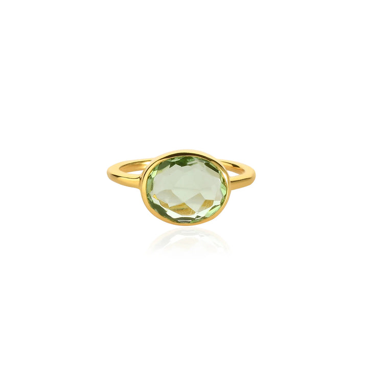 The Shyla Oval Chunky Ring features a large, faceted light green gemstone in a simple bezel setting with a thick gold band, shown against a white background.