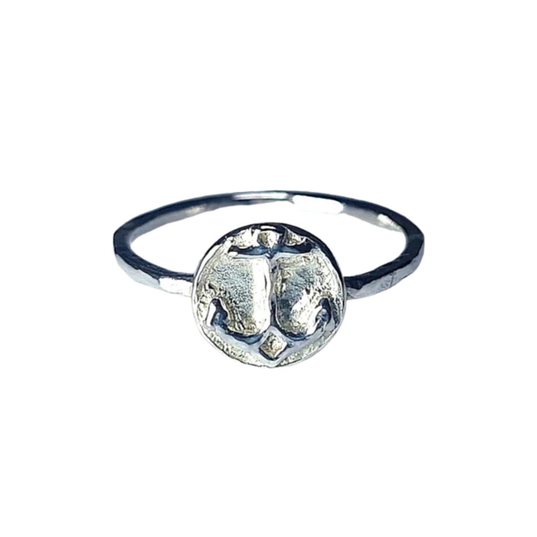 The Odyssey Ring by Pale Raven features a round, textured silver face with an abstract pattern and a thin band, offering modern elegance. Its unique design adds everyday luxury to your look.