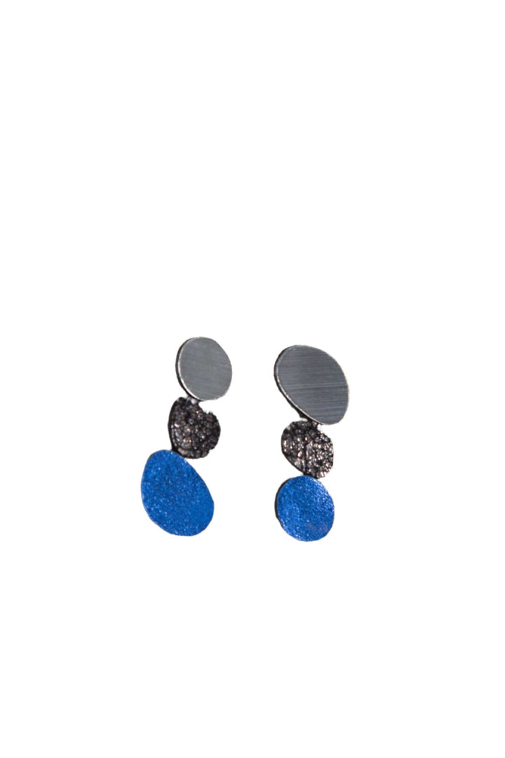 Presenting the Iskin Sisters' Organic Reflections Earrings: minimalistic dangle earrings featuring three linked segments. A small silver disc sits at the top, followed by a textured black oval in the middle, and a larger vibrant blue oval at the bottom—all beautifully showcased against a plain white background.