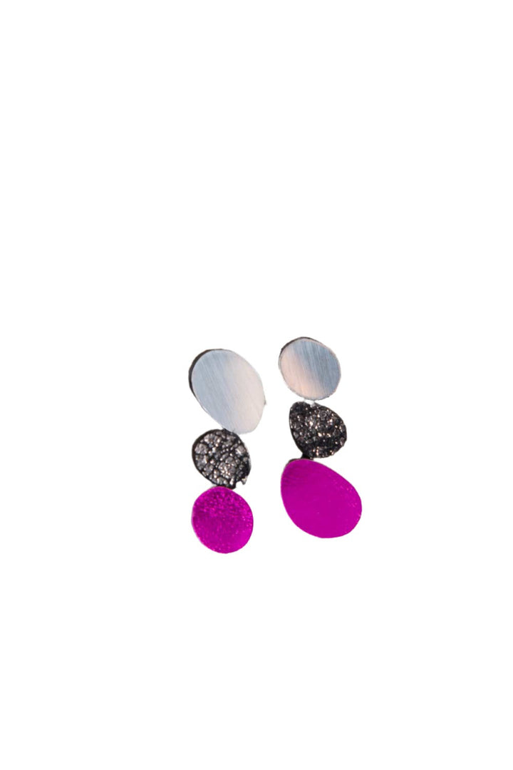 The Organic Reflections Earrings by Iskin Sisters are a pair of modern, abstract earrings featuring four unevenly shaped, round pieces in each earring. The top piece is silver, followed by two dark speckled pieces and a bright pink piece at the bottom. This handcrafted jewelry is beautifully displayed on a white background.