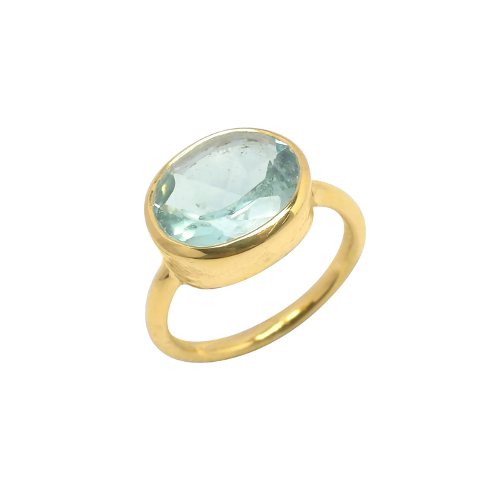 The Shyla Oval Chunky Ring features a gold band with a large, pale blue oval crystal in a simple bezel setting, shown against a white background.