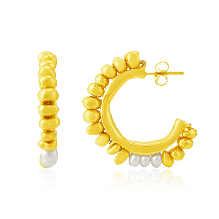 A pair of Pebble Pearl & Gold Hoop Earrings by Shyla featuring a unique, irregular beaded design in gold. One end of each hoop earring is adorned with a single silver bead. The earrings are displayed both from the side and front views against a white background.