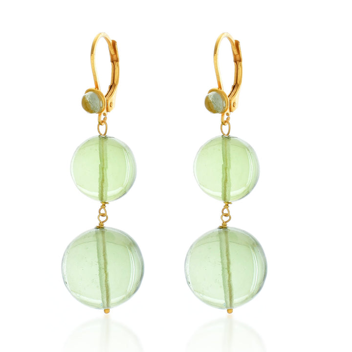 The Shyla Pernille Earrings are a pair of elegant earrings featuring 22 carat gold clasps. Each earring has two large, translucent green beads linked vertically, with a smaller matching bead connecting to the clasp. The overall design is simple and sophisticated, offering a refined aesthetic.