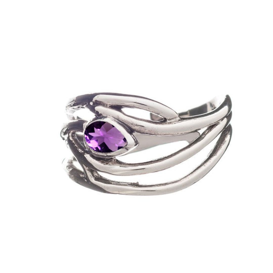 The Peacock Ring by Gallardo & Blaine Designs features a unique, abstract design in sterling silver with flowing curves, centered on an oval-cut purple gemstone, set against a pristine white background.