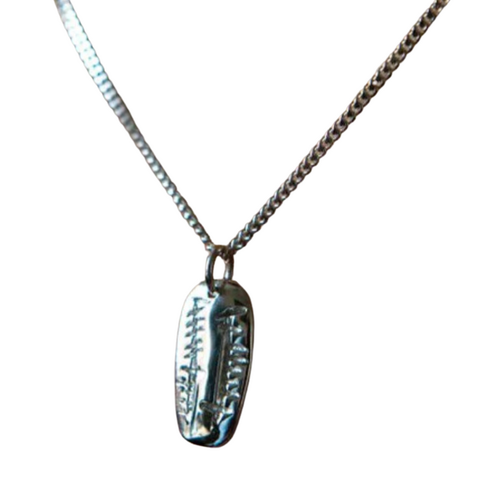 Close-up of the Ogham Treasure Soul Friend (Anam Cara) Carved Pendant, featuring vertical and horizontal lines resembling tally marks. The pendant hangs on a simple, thin chain against a white background, evoking the essence of an Anam Cara or soul friend.