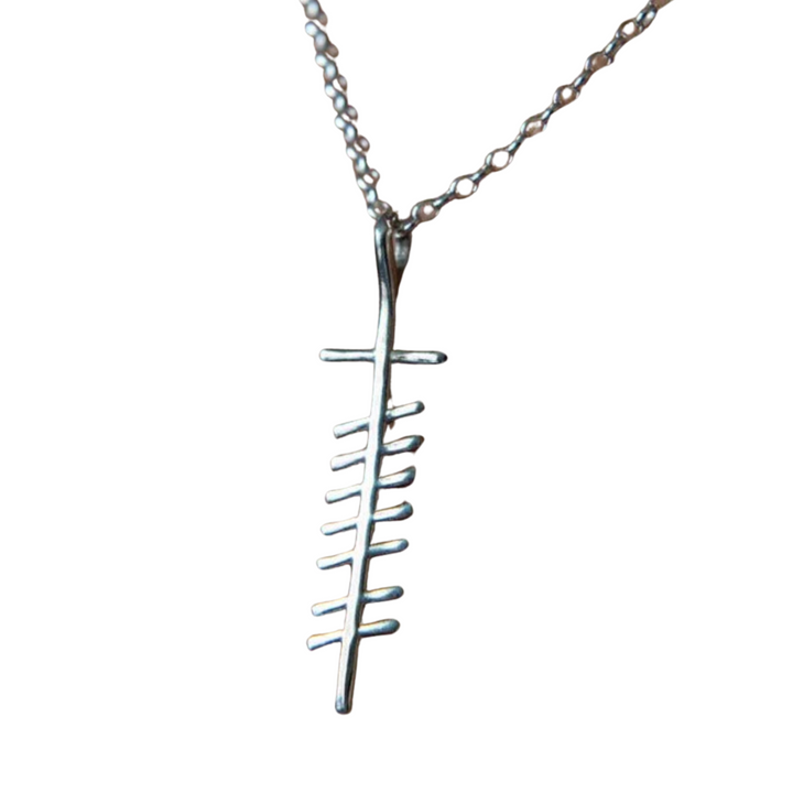 An Ogham Treasure Love (Grá) Unisex Pendant features a stylized fish skeleton, with bones represented by simple vertical bars aligned along a central spine. Hanging from a delicate chain with small, evenly spaced links, this unique piece subtly evokes the elegance of ancient Ogham script.