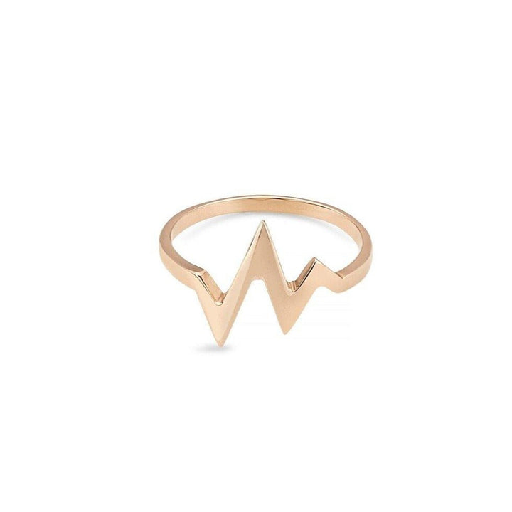 A 9ct Gold Heartbeat Ring by Cosmic Boulevard with a unique design featuring a zigzag pattern resembling a heartbeat or electrocardiogram line. The band is simple and elegant, highlighting the central geometric shape. The background is plain white.