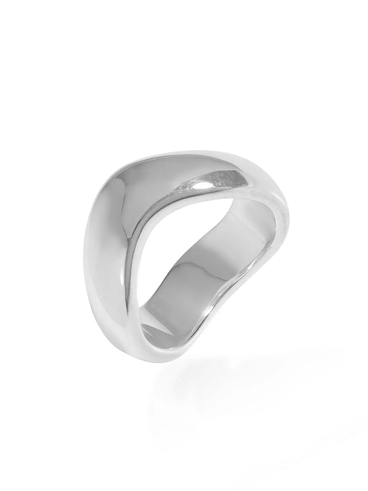 The Rocco Ring by Shyla is a shiny, abstract silver ring with a smooth, asymmetrical design set against a white background. Its chunky, sculptural form offers a modern appearance, making it timelessly elegant and stylish.