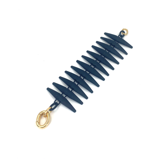A spiked black bracelet made of 3D printed Nylon with gold clasps on a plain white background. 