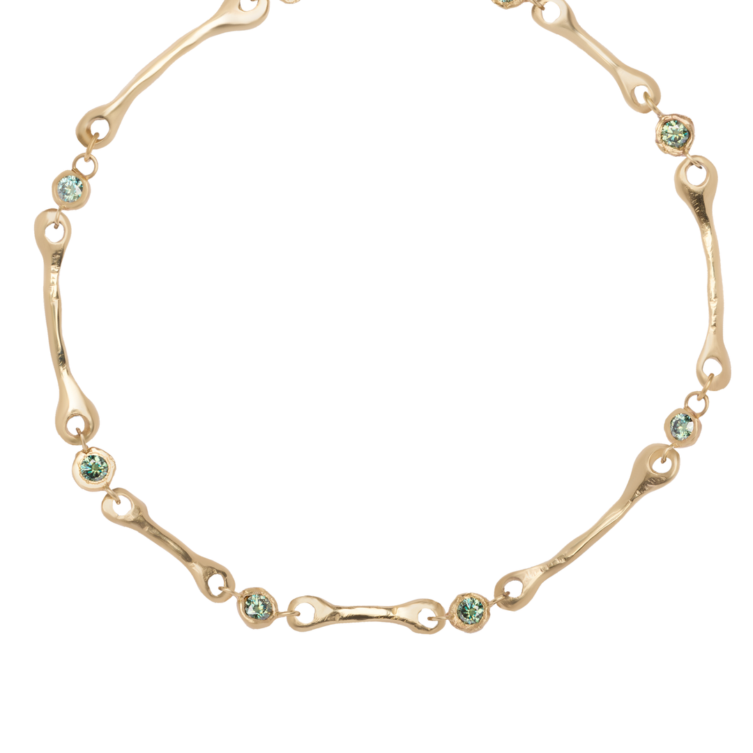 The Relic Necklace by Madeleine Sculptural Jewellery features irregularly shaped gold links and round, light blue gemstones arranged evenly along the chain, displayed on a white background.