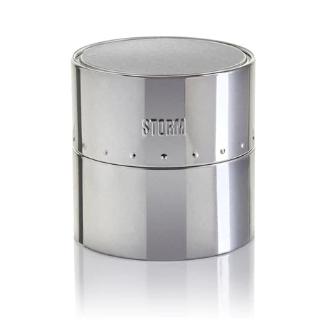 A sleek, silver cylindrical container with a smooth surface and the word "Storm Excepto Green" etched on the front. The container has a modern, minimalist design, much like a high-end watch by Storm Watches. It's divided into two sections with a subtle seam around the middle, embodying both elegance and functionality.