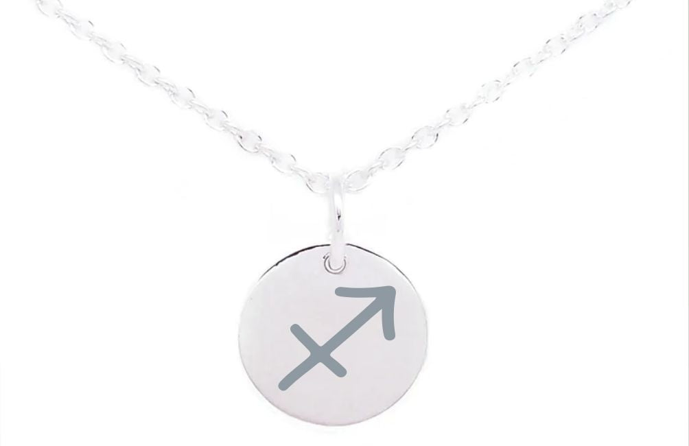 A Horoscope Large Disc Charm Silver by Personalised Charms features a round pendant with the Sagittarius zodiac sign, an arrow pointing diagonally upwards to the right. The chain is slightly twisted, and the image has a white background.