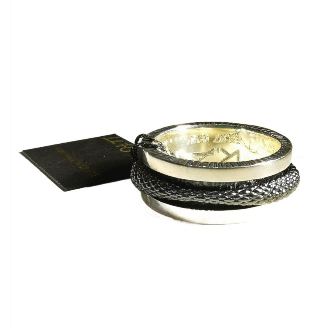 The Scaled Texture Silver Spinner Ring by K.And features elegant silver with engraved details, blending style and fidget design for subtle stress relief. Displayed on a white background.