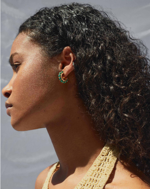 A woman with curly hair is shown in profile, wearing the Shyla Rosalia Hoop Earrings and a beige crocheted top against a light, neutral background.