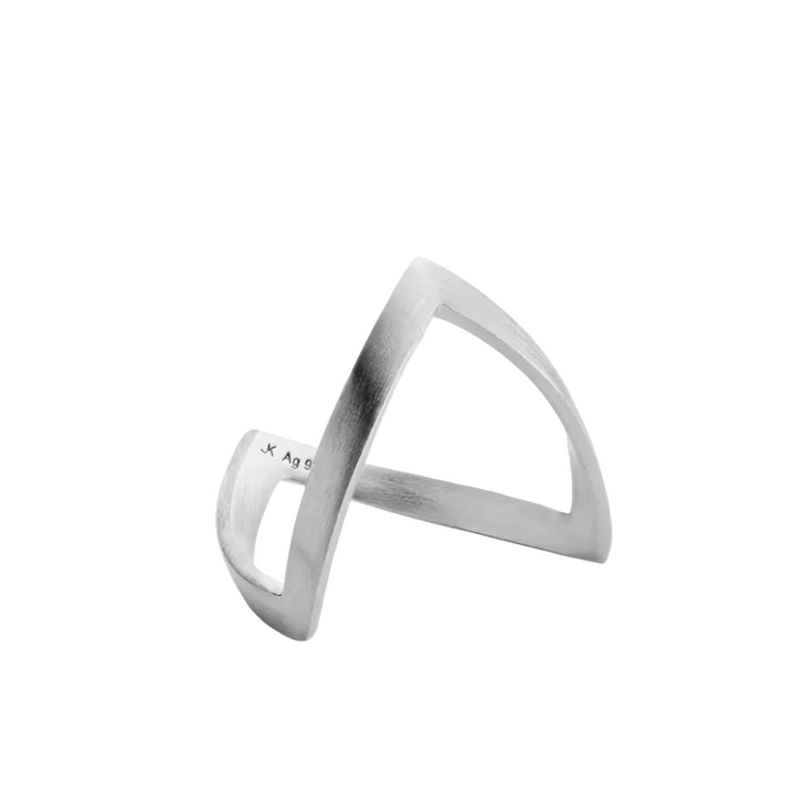 The Jane Koenig V Ring is a minimalist sterling silver piece with an open, angular design featuring two thin, asymmetrical bands that intersect to form striking geometric shapes reminiscent of a modern V ring, showcased against a plain light gray background.