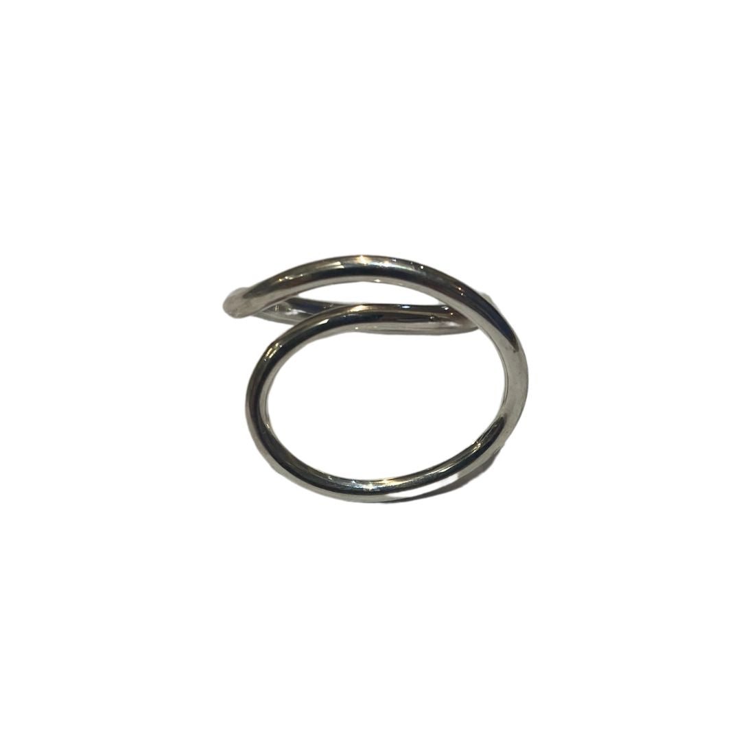 The Sea Honey Ring by Gallardo & Blaine Designs boasts a minimalist, open-ring design in sterling silver. One end curves upward and the other downward, creating an elegant spiral that exudes effortless sophistication against a plain white backdrop.