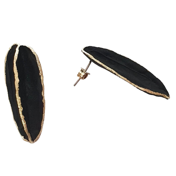 Two black, leaf-shaped, handmade Georgia Charal Leaf Earrings with gold edges. One earring stands upright, displaying its front, while the other lies flat, showcasing its back and the post with a gold-tone butterfly clasp. They are placed on a white background.