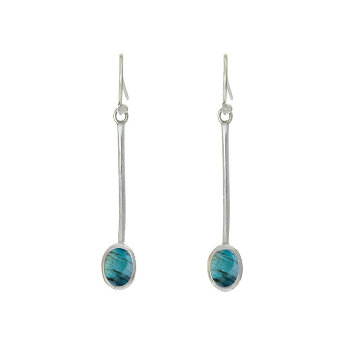 The Sequola Earrings by Gallardo & Blaine Designs feature sterling silver bars with marbled oval turquoise gemstones, offering timeless charm. They have simple hooks for wearing and are set against a white background.