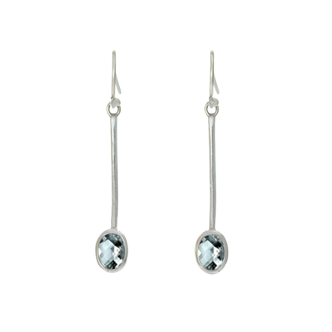 The Sequola Earrings by Gallardo & Blaine Designs feature two elegant sterling silver pieces, showcasing timeless charm with slender stems and symmetrical oval, faceted blue gemstones against a white backdrop.