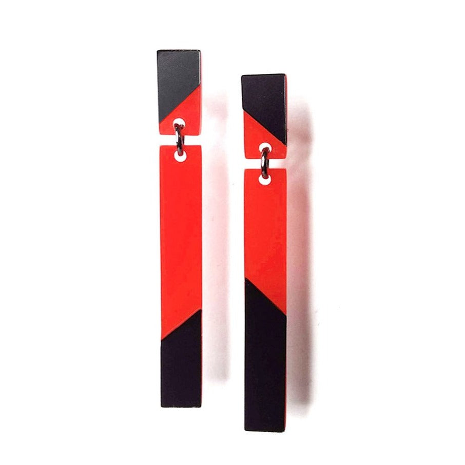 A pair of rectangular drop earrings with a modern design, handcrafted in Paris. Each earring features red and black geometric patterns divided diagonally. The upper half has a small rectangle joined to a longer strip by a metal ring, creating stylish Sterling Silver Lenny post & drop earrings by Alex + Svet with retro-futuristic flair.